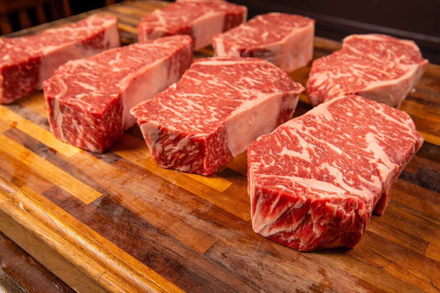 Raw ground beef steaks on a wooden cutting board
