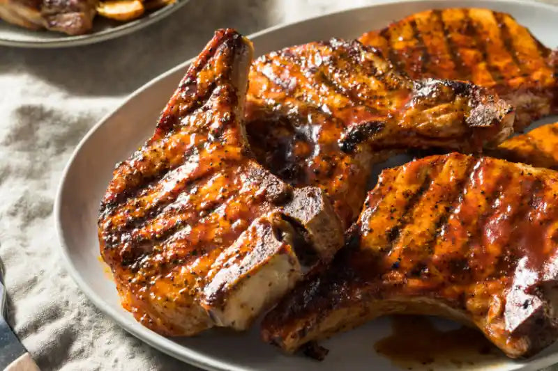 Grilled bone-in pork chops served with a Bloody Mary-style tomato salad made with cherry tomatoes, celery, and fresh herbs.